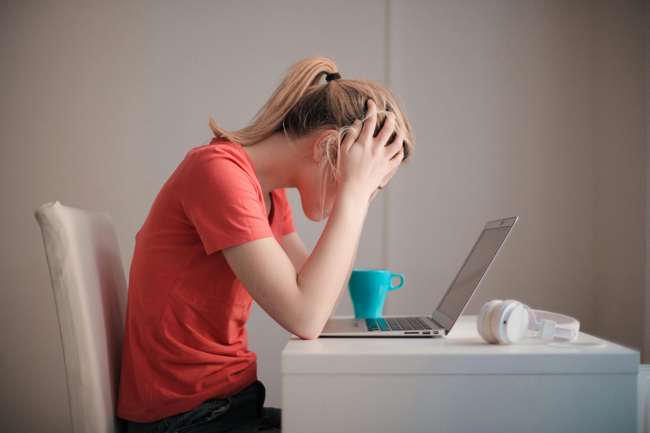 woman scratching her head while sitting in front of a slow laptop